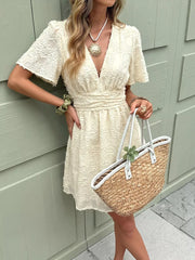 Chic apricot textured mini dress with ruched waist and deep V-neck