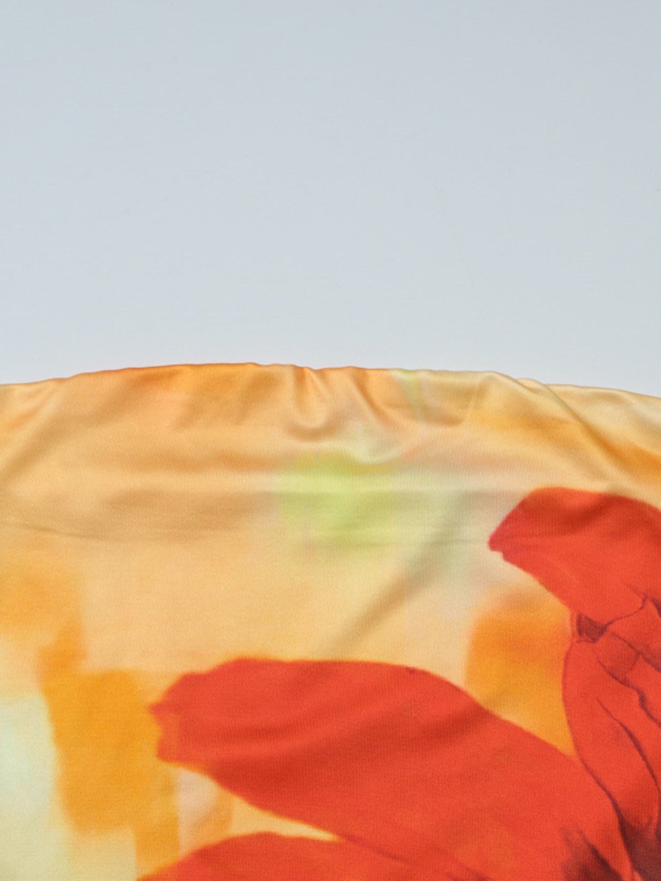 Strapless tube top with abstract floral print in orange and yellow hues.