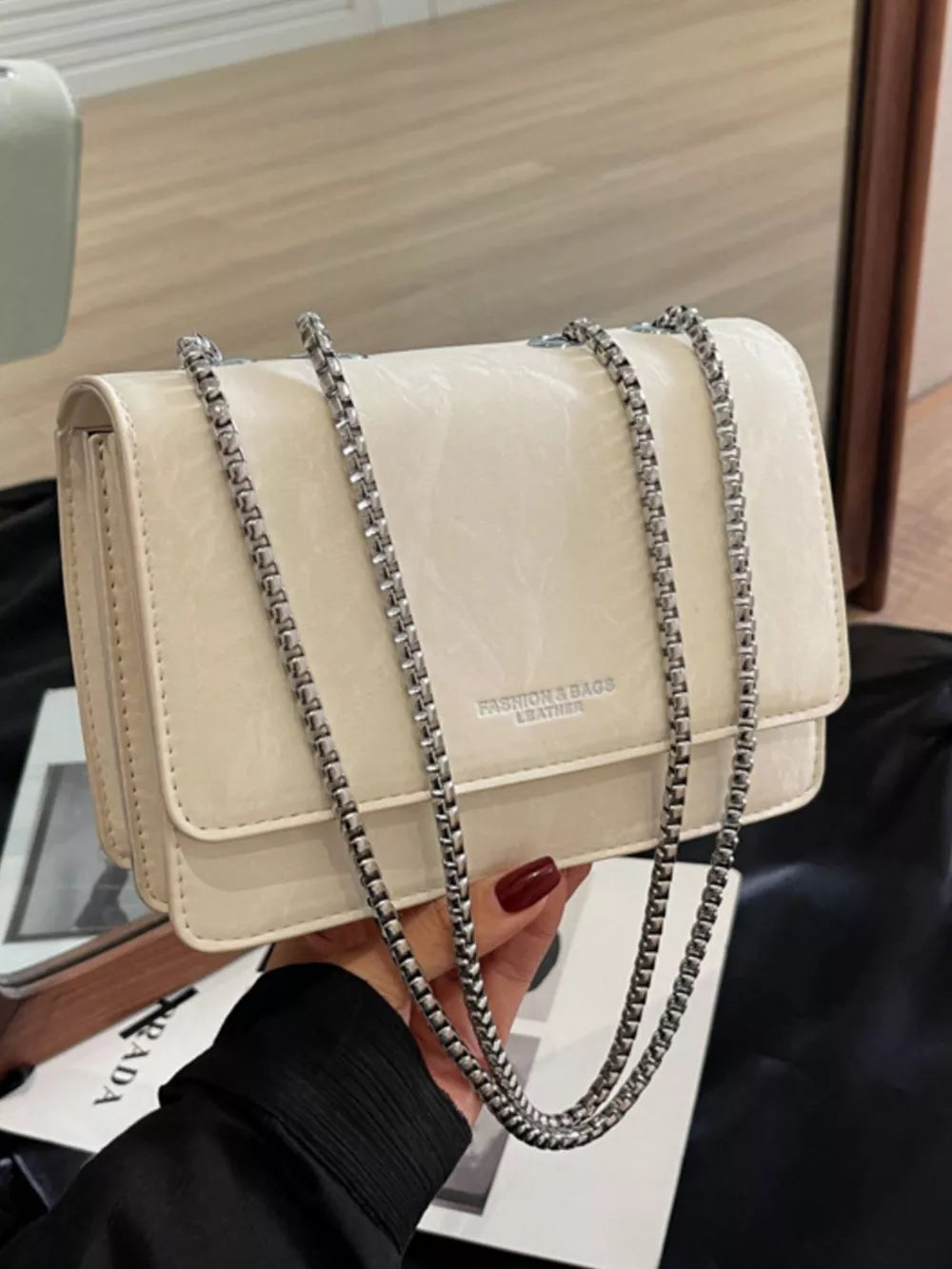 Beige leather shoulder bag with crumpled texture and silver chain strap.