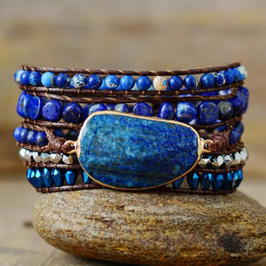Bohemian wrap bracelet with blue stones and beads on brown cord, featuring a large central stone.