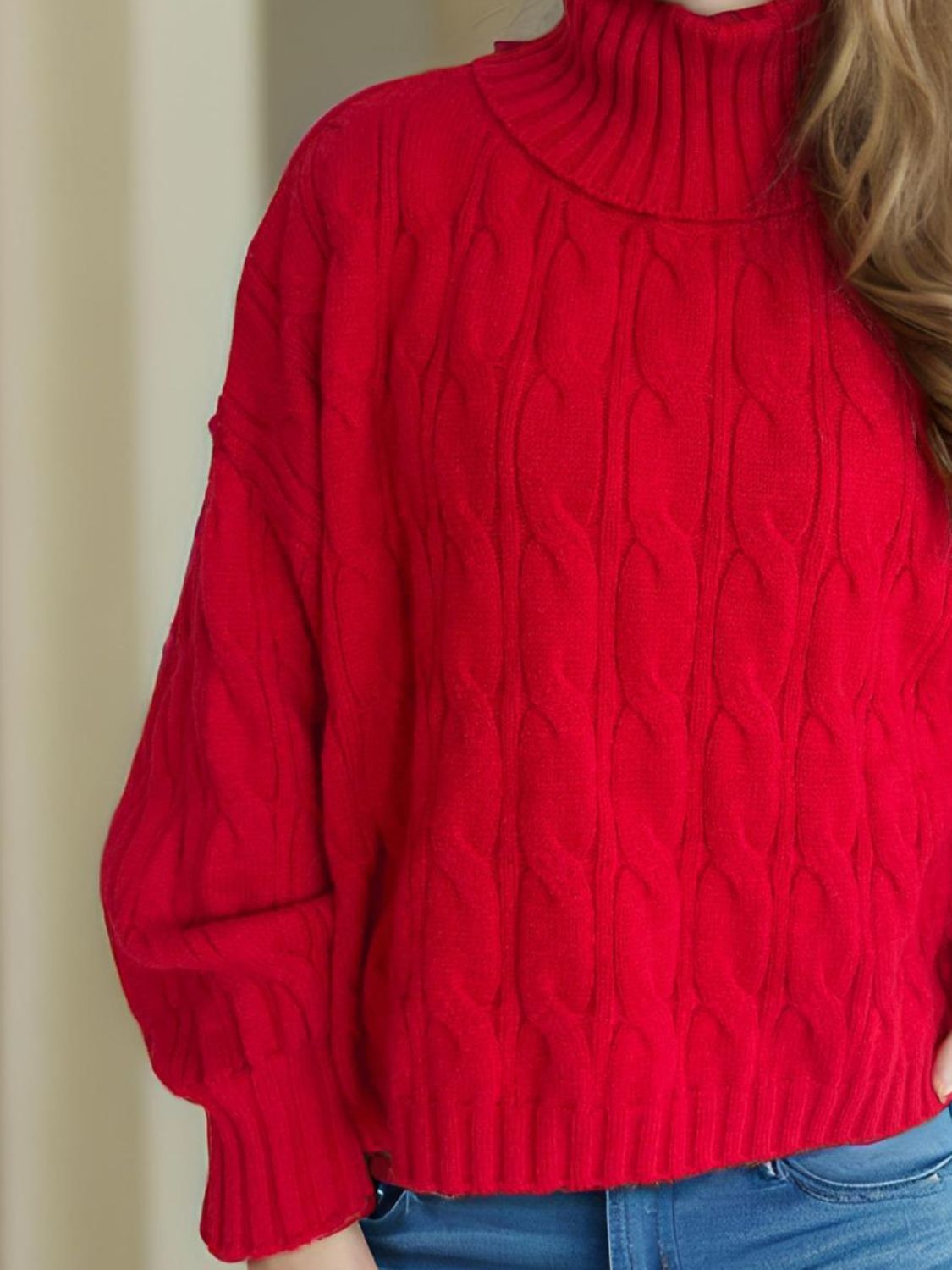 Oversized red cable knit turtleneck sweater with ribbed details.