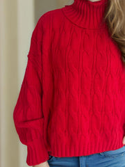 Oversized red cable knit turtleneck sweater with ribbed details.