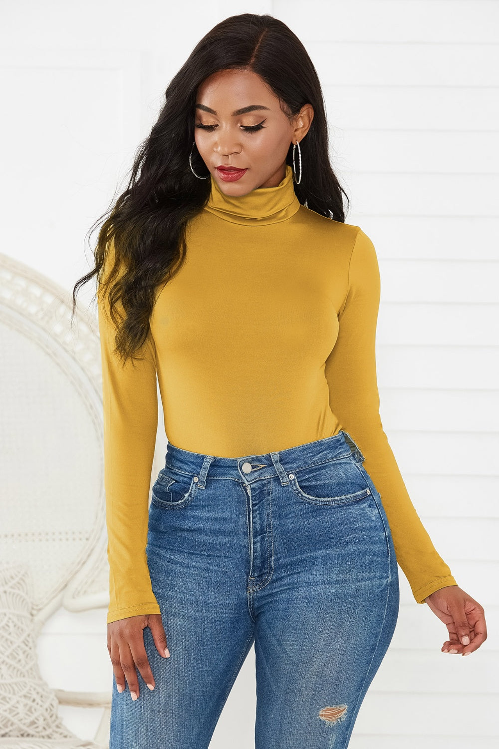 Gold turtleneck bodysuit with long sleeves, paired with distressed denim jeans.