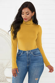 Gold turtleneck bodysuit with long sleeves, paired with distressed denim jeans.