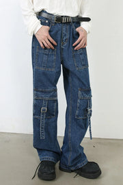 Utility denim cargo pants in medium wash with buckle strap pocket details and wide leg cut.