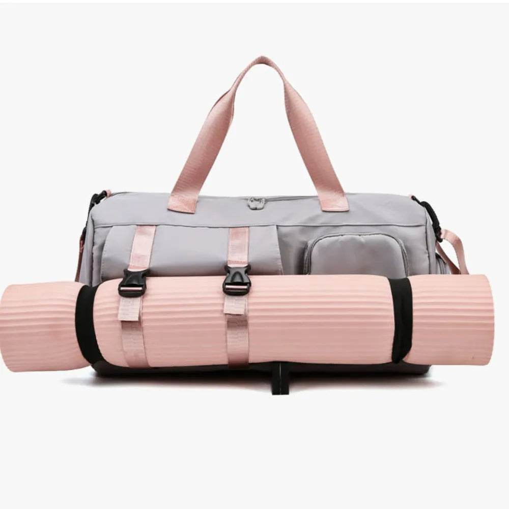 Gray gym duffel bag with pink straps and buckle details, holding a pink yoga mat.