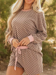 Chic checkerboard loungewear set with pink trim, featuring a pullover and drawstring shorts.