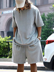 Men's light gray relaxed fit shorts with drawstring waist and raw hem detail.