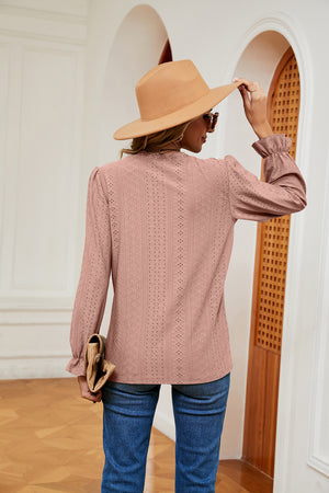 Dusty pink perforated blouse with ruffle cuffs and long sleeves.