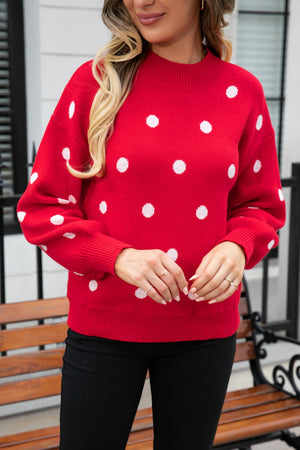 Red polka dot knit sweater with balloon sleeves and mock neck.