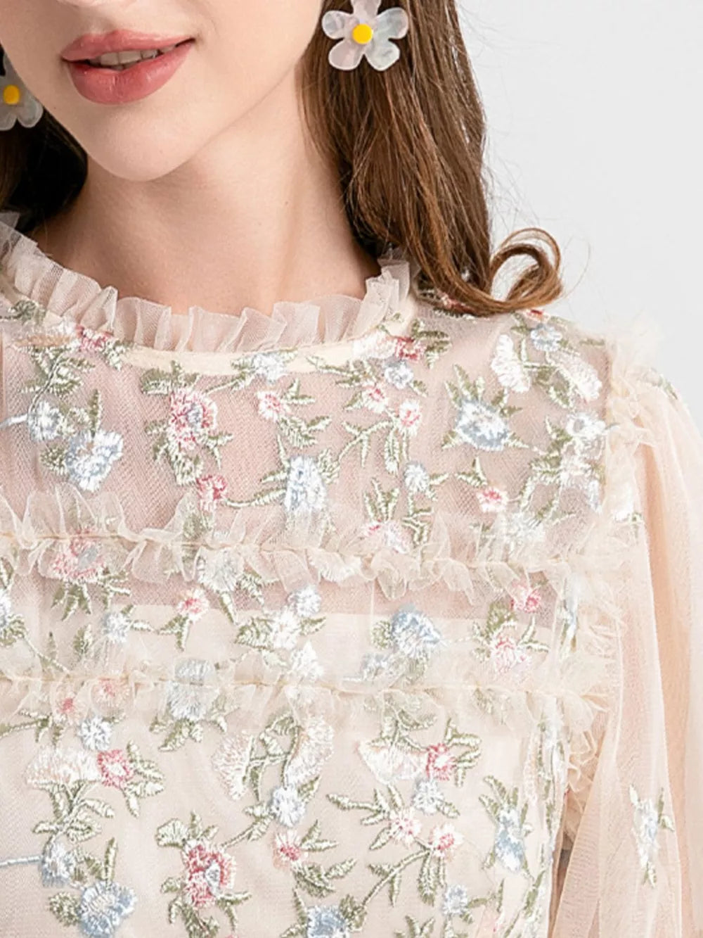 Embroidered floral tulle maxi gown with ruffled neckline and sleeves in a light peach hue.