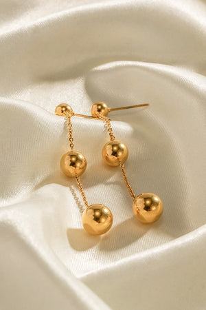 Gold triple orb drop earrings with delicate chains and a bold design.