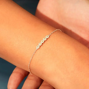 Silver daisy chain bracelet with delicate flower charms and a thin chain.
