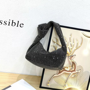 Black crescent tote bag covered in rhinestones with a knotted strap.