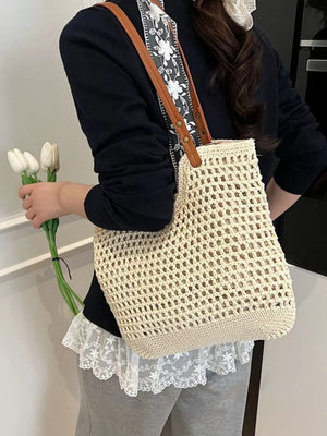 Beige woven straw shoulder bag with leather straps and floral detail strap.