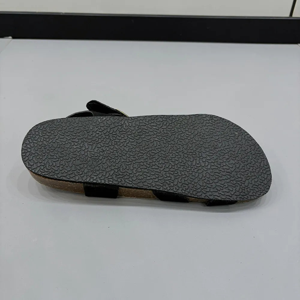 Black suede crossover buckle cork sandals with textured sole detail.