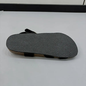 Black suede crossover buckle cork sandals with textured sole detail.