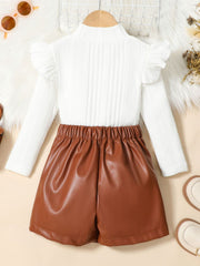 White ribbed knit top with ruffled sleeves and brown faux leather shorts.