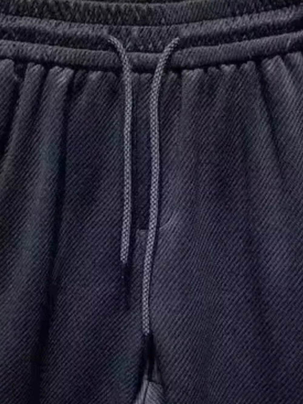 Black drawstring boxer shorts with textured fabric and pockets.
