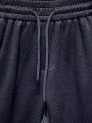 Black drawstring boxer shorts with textured fabric and pockets.