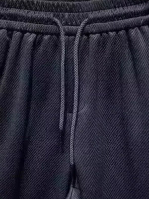 Black drawstring boxer shorts with textured fabric and pockets.