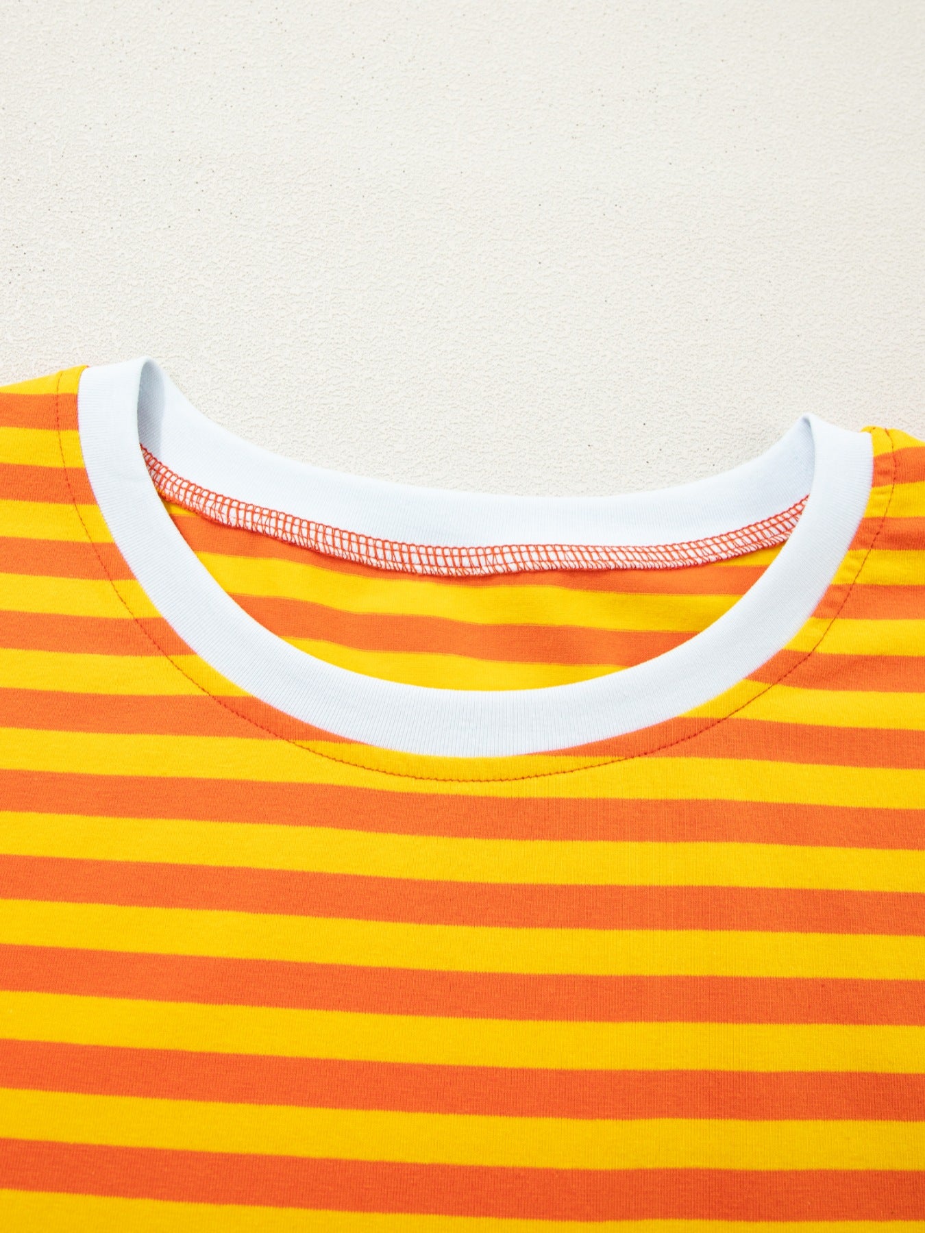 Striped round-neck casual t-shirt in tangerine and yellow cotton with white trim.