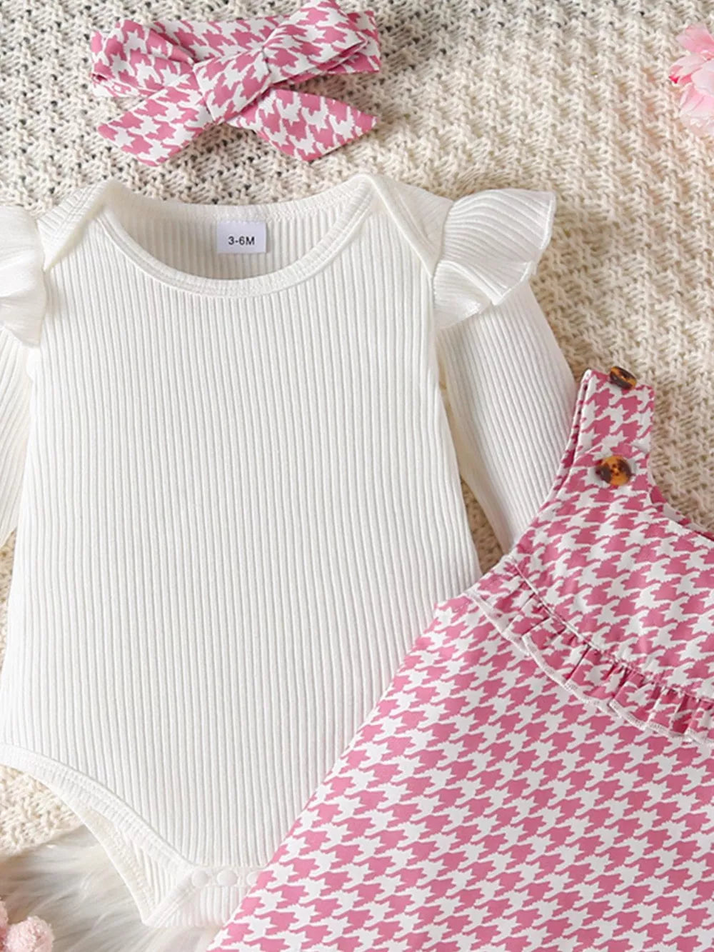 White ribbed bodysuit with ruffled sleeves and pink houndstooth dress with bow headband