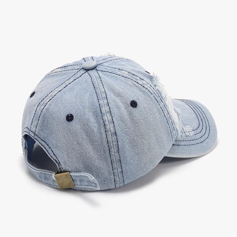 Light denim baseball cap with distressed shredded details and adjustable strap.