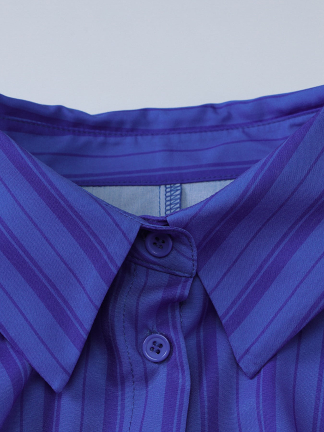 Button-down mini dress in blue with purple stripes, featuring a collar and visible buttons.