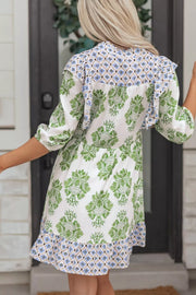 Mini dress with green floral print, ruffled neckline, and patterned hem.