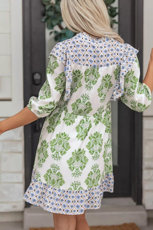 Mini dress with green floral print, ruffled neckline, and patterned hem.