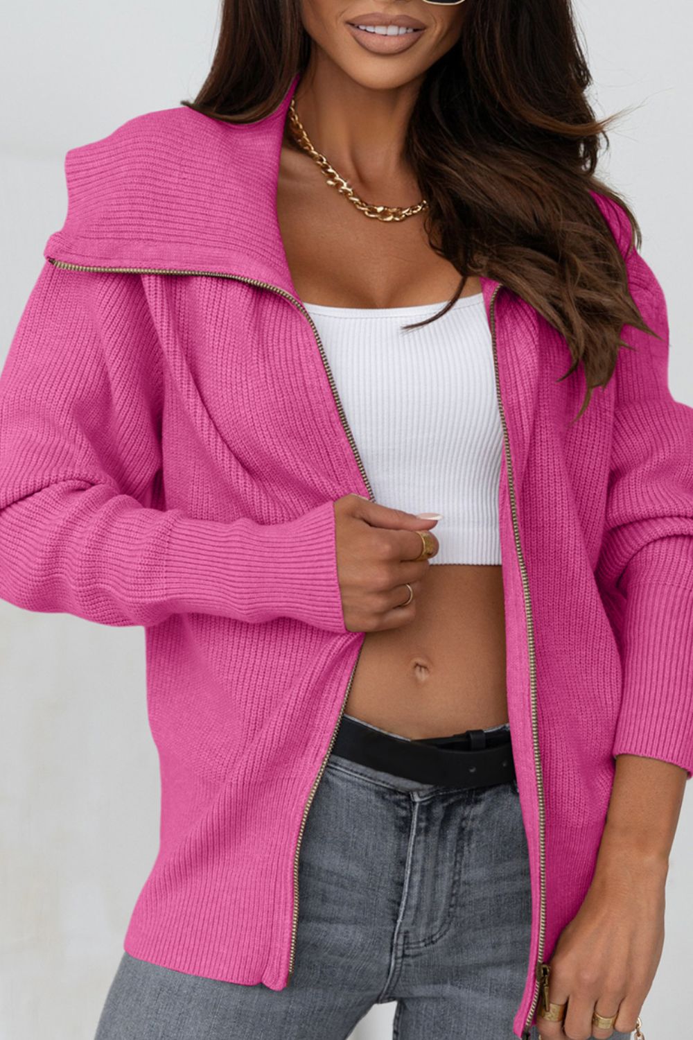 Hot Pink ribbed knit cardigan with shawl collar and zip front, styled with a white crop top and grey jeans.
