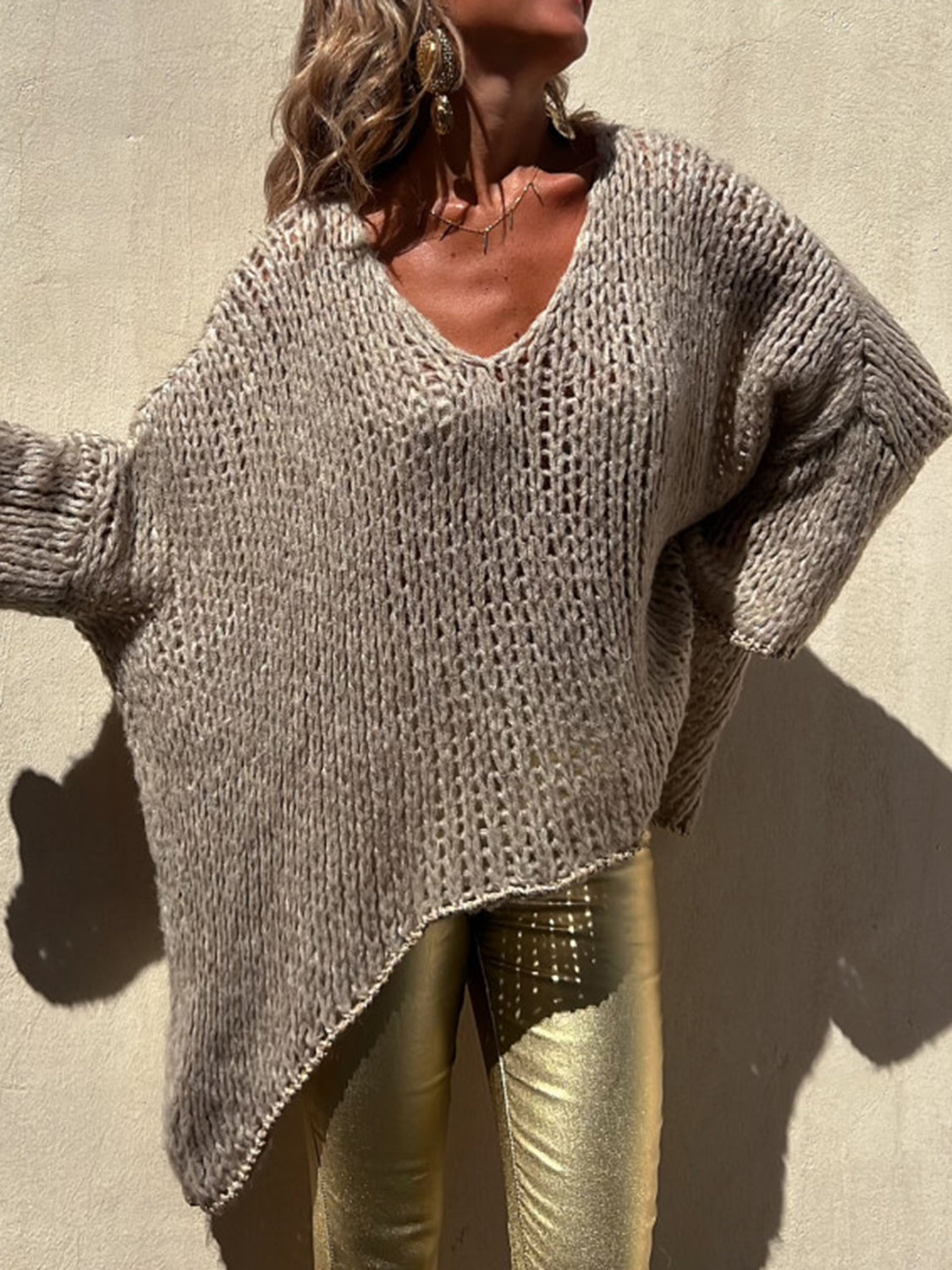 Camel open knit sweater with V-neck and asymmetric hem, featuring beaded trim detail.