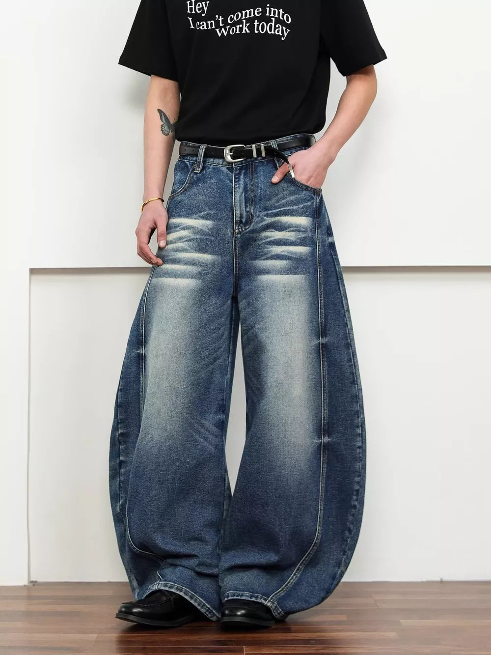 Belted wide leg jeans in dark blue denim with a balloon silhouette and distressed details.