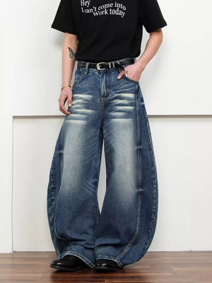 Belted wide leg jeans in dark blue denim with a balloon silhouette and distressed details.