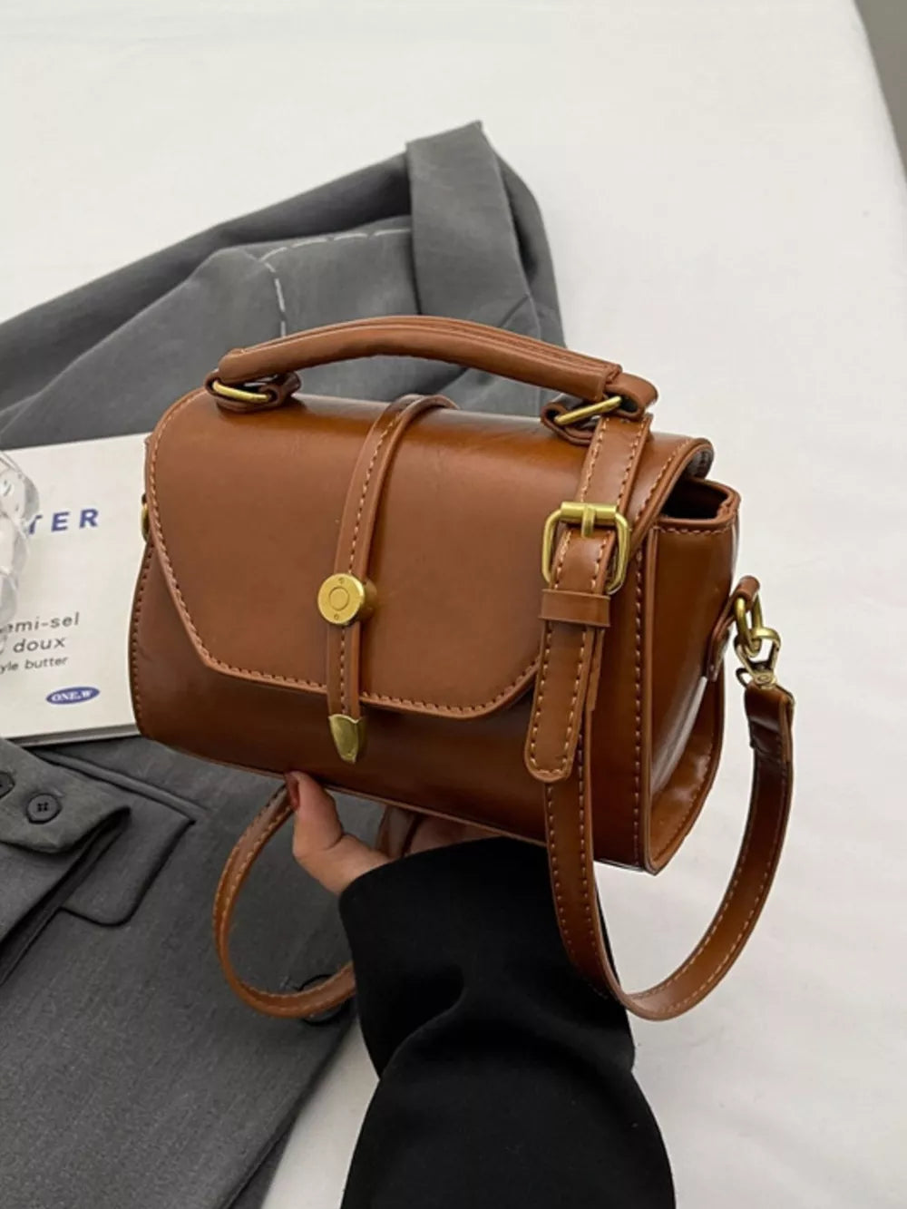 Brown pu leather mini crossbody bag with clasp and adjustable strap.