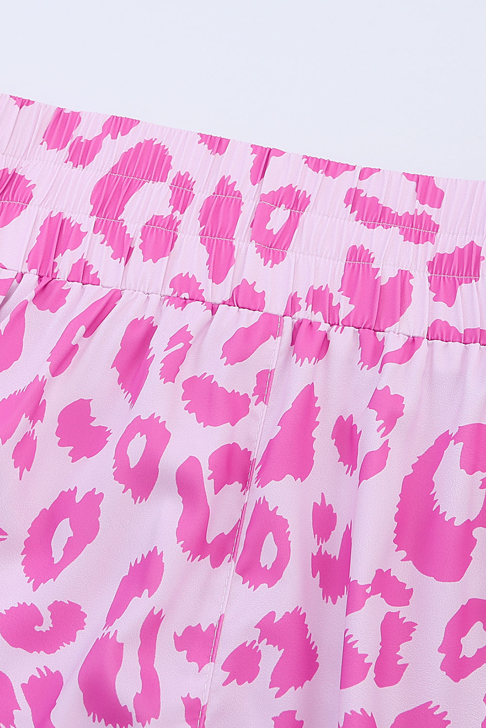 Pink leopard print shorts with elastic waistband and scalloped hem detail.