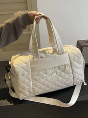 Diamond-stitched beige quilted duffel bag with adjustable strap and front logo detail.