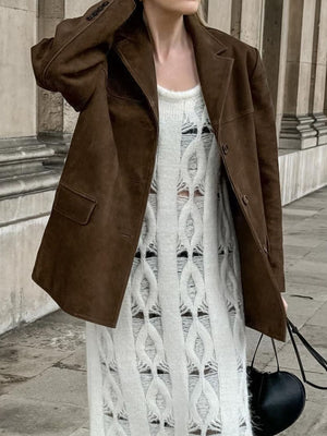 Brown suede blazer with structured shoulders and button closure, worn over a white distressed knit dress.