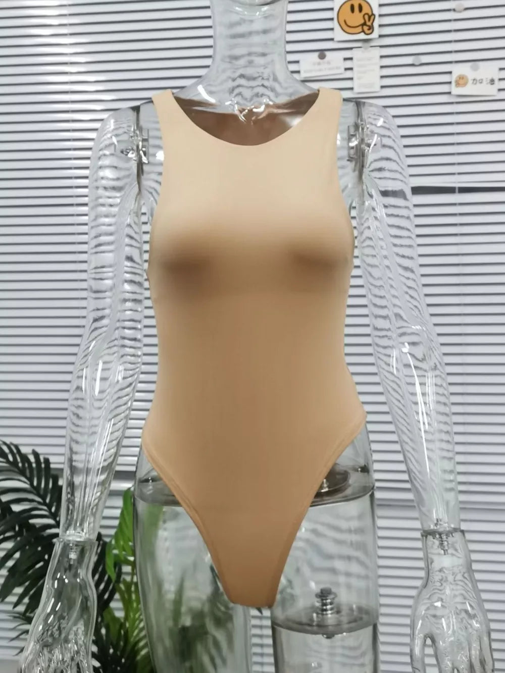 Skin color round neck sleeveless bodysuit with a high-cut leg.