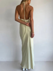 Yellow satin halter maxi dress with asymmetric cut and open back detail.