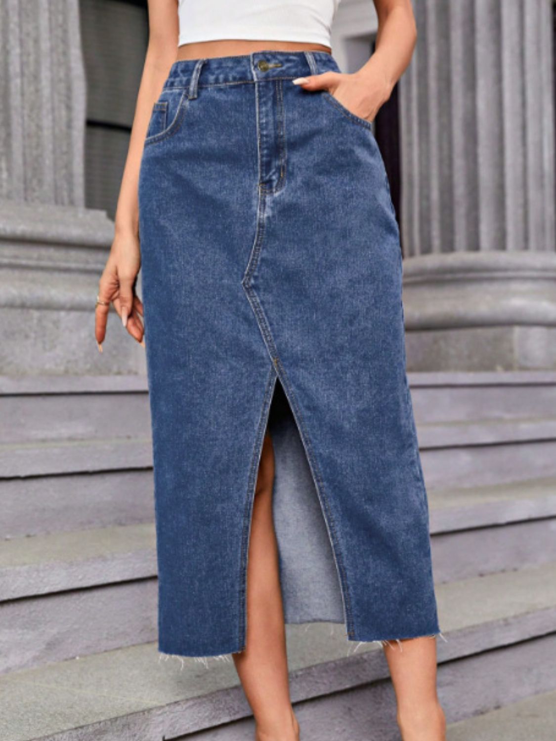 Medium wash denim maxi skirt with front slit and frayed hem