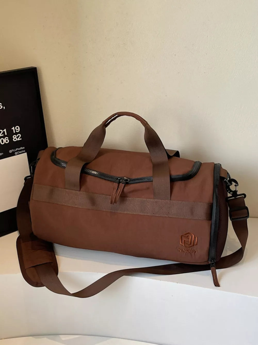 Brown Oxford cloth duffel bag with carry handles and adjustable strap
