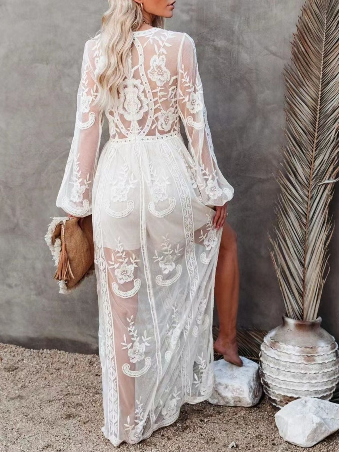 White floral lace maxi dress with long bell sleeves and a high slit, showing a sheer overlay.