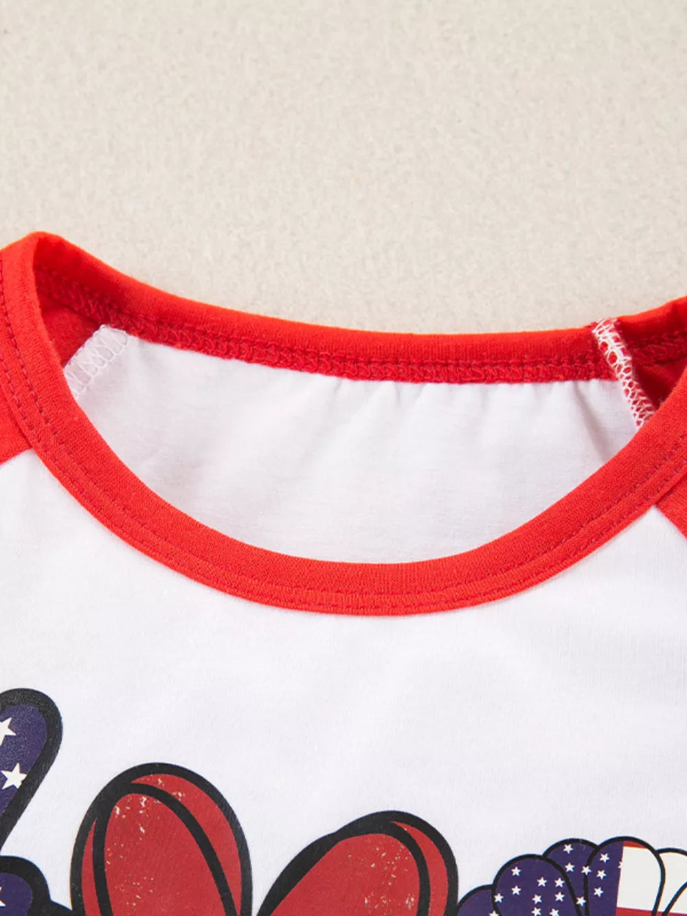 Baby raglan tee with patriotic graphic and red trim.