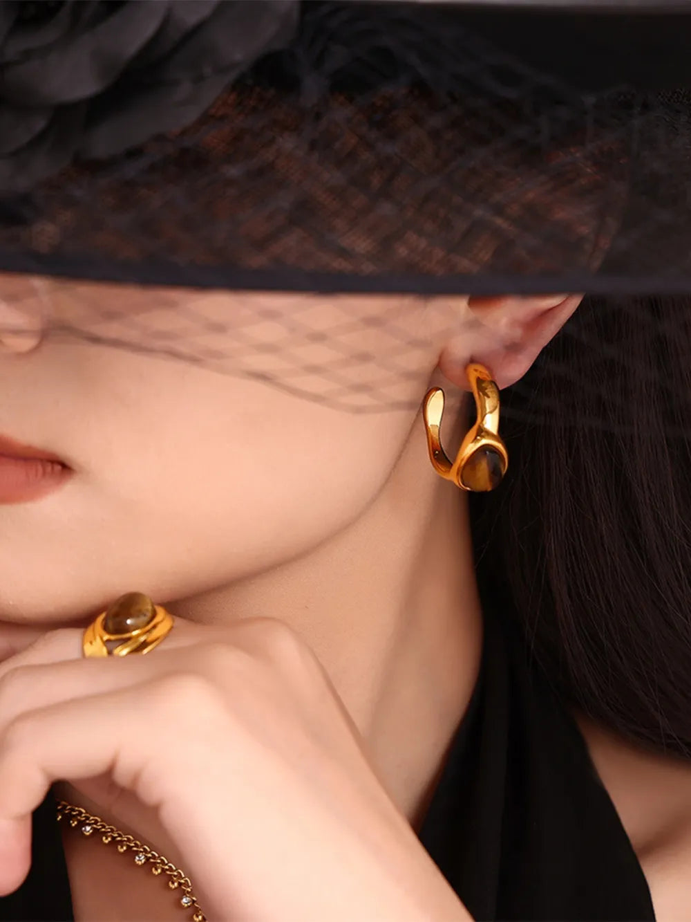 Gold sculptural hoop earrings and ring with tiger's eye stone accents.