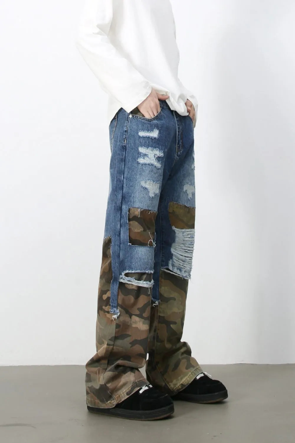 Distressed denim jeans with camouflage patchwork and baggy fit.