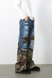 Distressed denim jeans with camouflage patchwork and baggy fit.