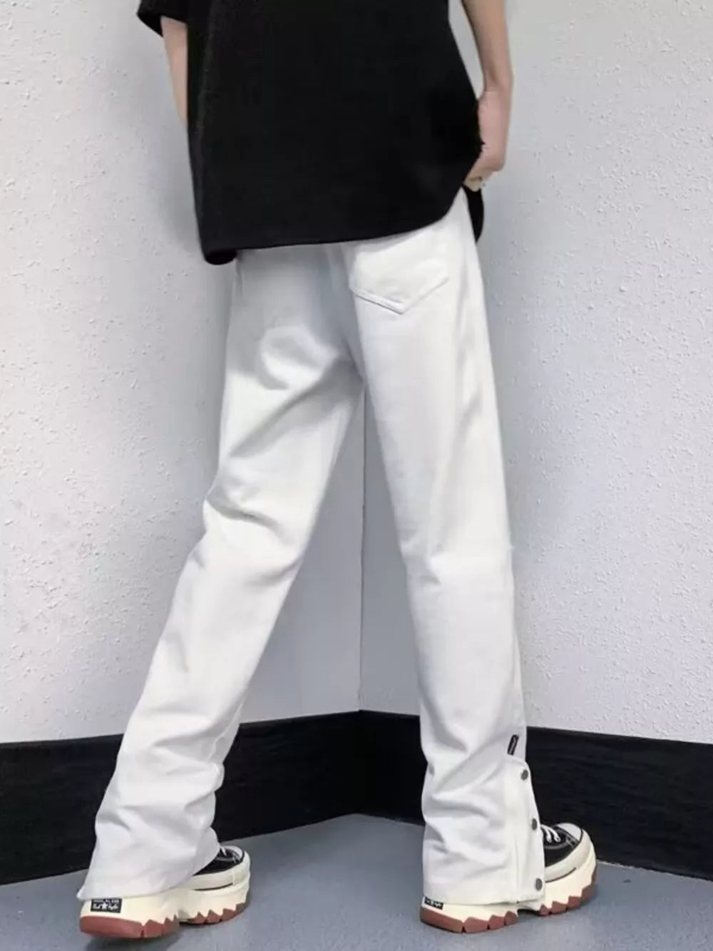 White distressed loose-fit jeans with snap detail at the hem