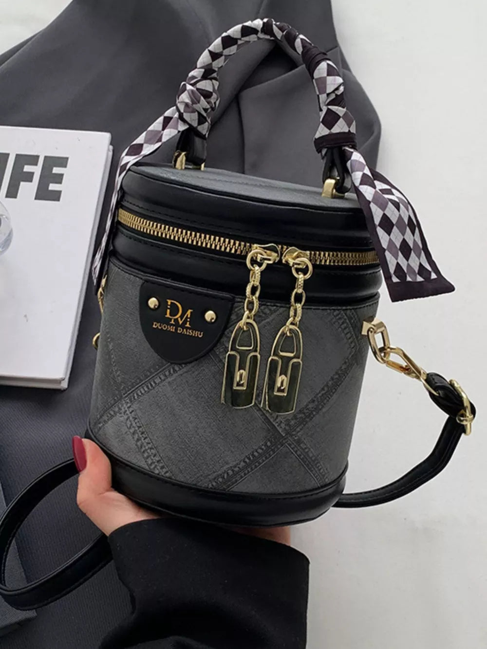 Black quilted mini bucket bag with checkered scarf detail on handle and gold hardware.